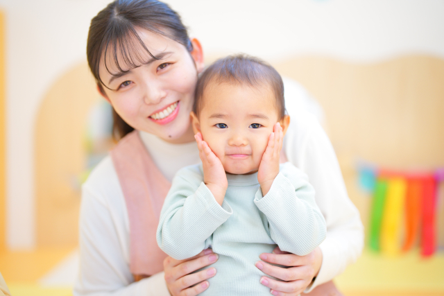 子どもを抱っこして笑顔を見せる保育士