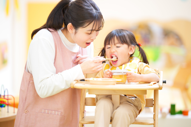 子どもの食事介助をする保育士