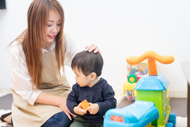 子どもをなでる保育士